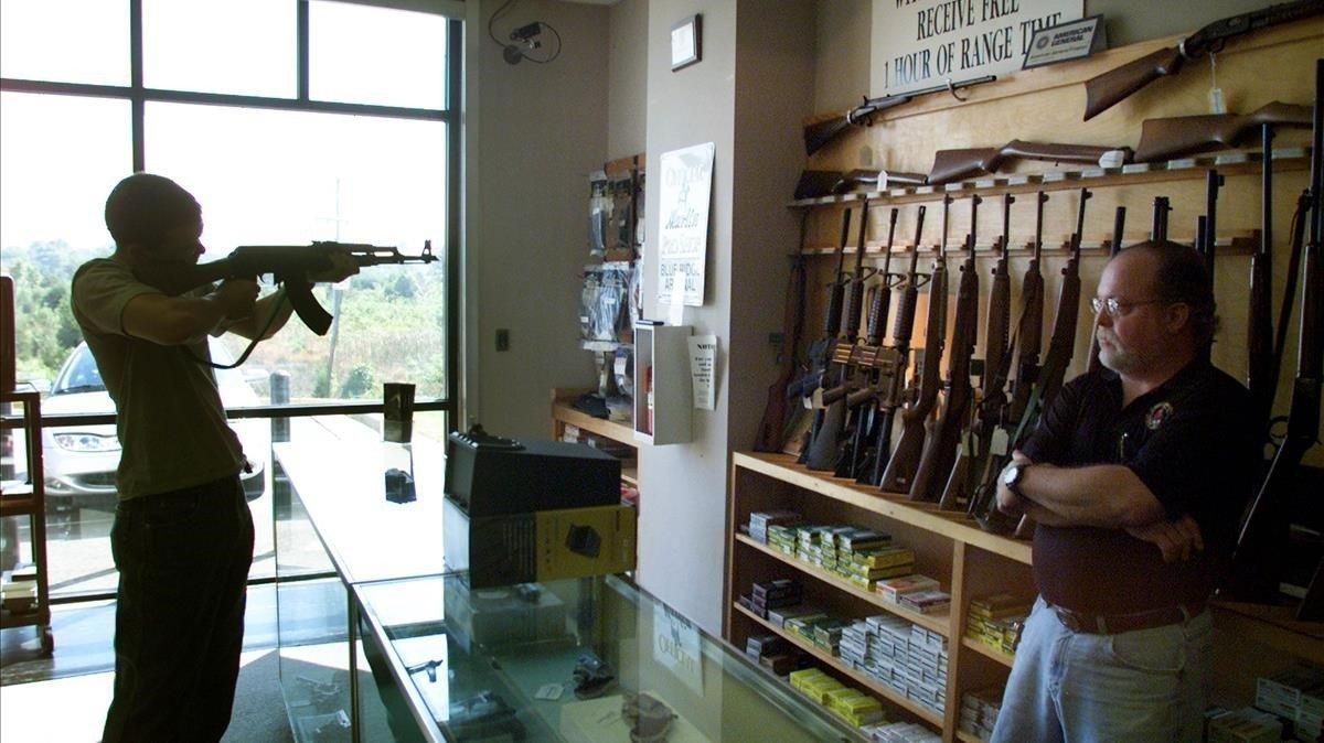 Un hombre prueba un rifle en una tienda de armas. Un hombre prueba un rifle en una tienda de armas.