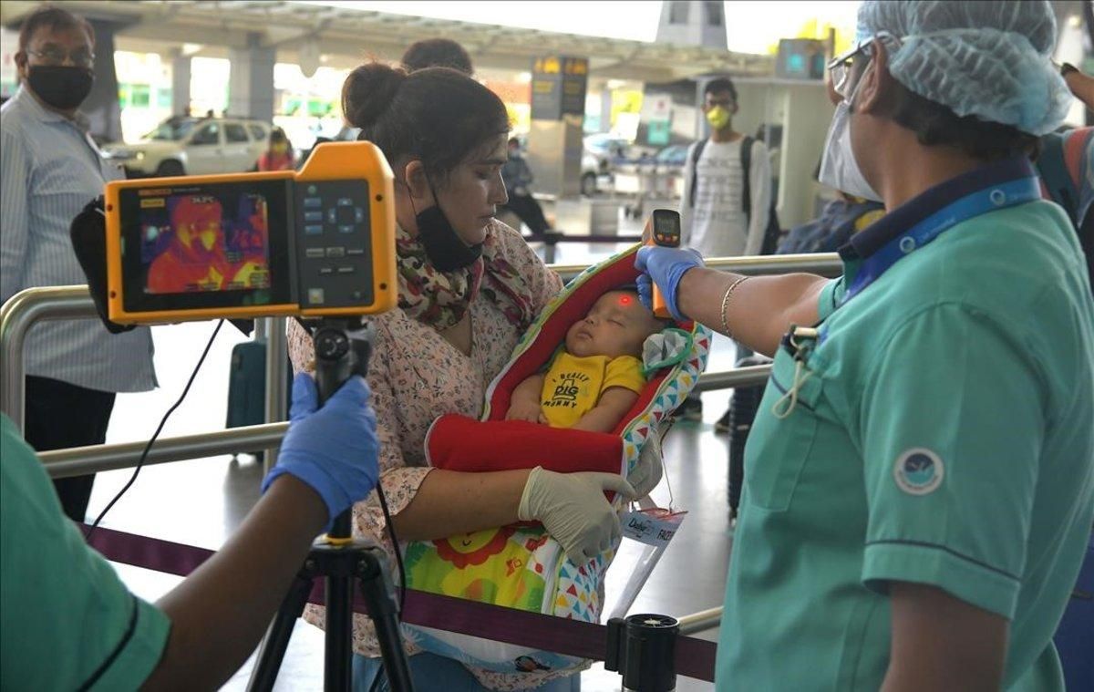 Personal del aeropuerto internacional de Bangalore toma la temperatura a una madre y su bebé, el 25 de mayo. Personal del aeropuerto internacional de Bangalore toma la temperatura a una madre y su bebé, el 25 de mayo.