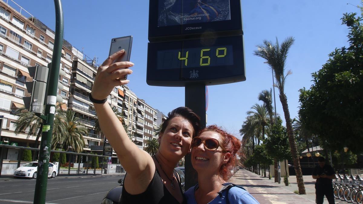 Unas mujeres se hacen un ’selfie’ ante un termómetro callejero en Córdoba, en una imagen de archivo.