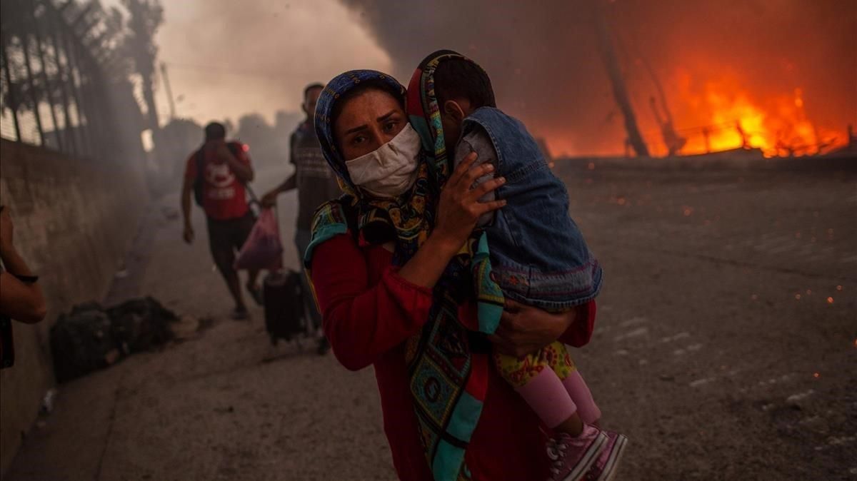 Una madre huyo con su hijos de las llamas en el campo de refugiados de Moria, en Lesbos. Una madre huyo con su hijos de las llamas en el campo de refugiados de Moria, en Lesbos.