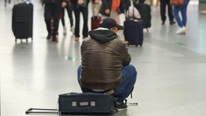Un viajero sentado sobre su maleta, en la estación de Atocha.