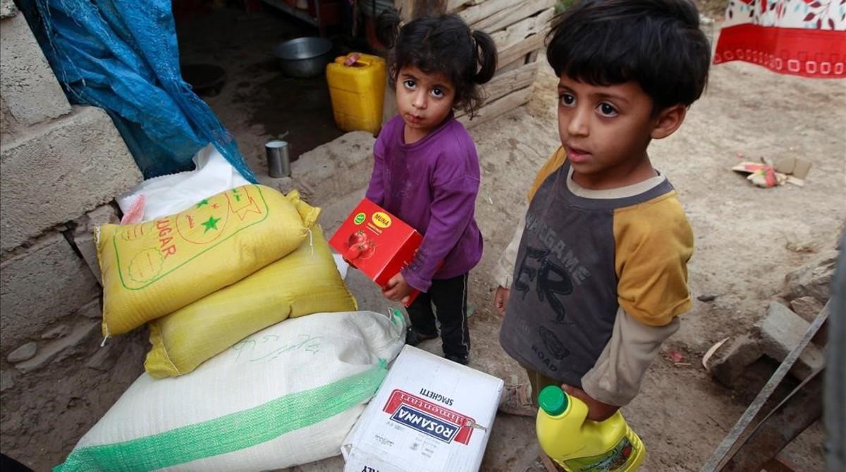 Dos niños yemenís junto a raciones de comida distribuidas por una organización benéfica local, el 15 de junio, en Saná.
