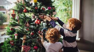 Unos niños decoran el árbol de Navidad.