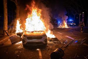 Coche de los policías de paisano ardiendo en la avenida de Maria Cristina.
