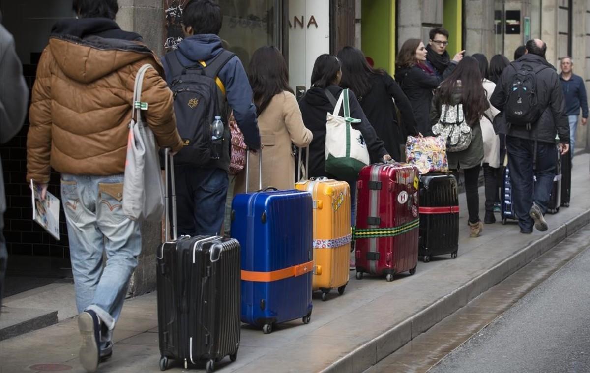Procesión de turistas y maletas por el centro de Barcelona.