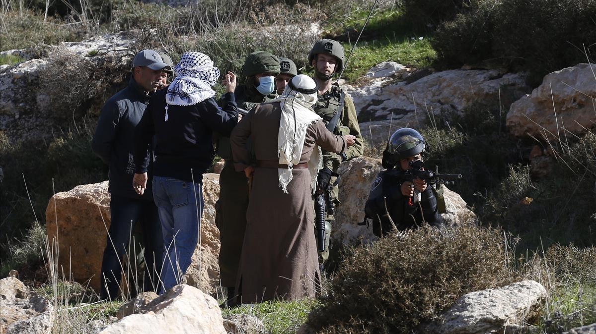 Dos palestinos discuten con soldados israelís durante una concentración en contra de un asentamiento en la ciudad de Naplusa, en Cisjordania, este viernes.