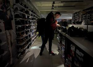 Varios clientes se ayudan con sus teléfonos móviles en una tienda de deportes durante un apagón en Kiev.