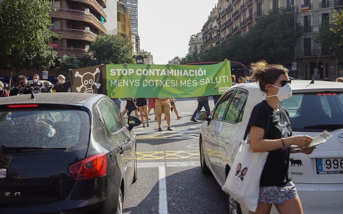Miembros de Eixample Respira despliegan una pancarta contra la contaminación en la calle de Aragó, esta tarde