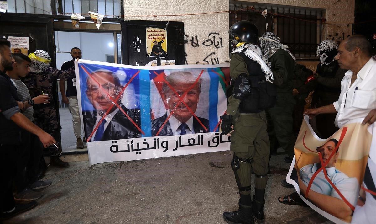 Unos palestinos se disponen a quemar imágenes de Mohamed bin Zayen, Binyamin Netanyahu y Donald Trump, tras conocerse el pacto entre Emiratos Árabes Unidos e Israel. 