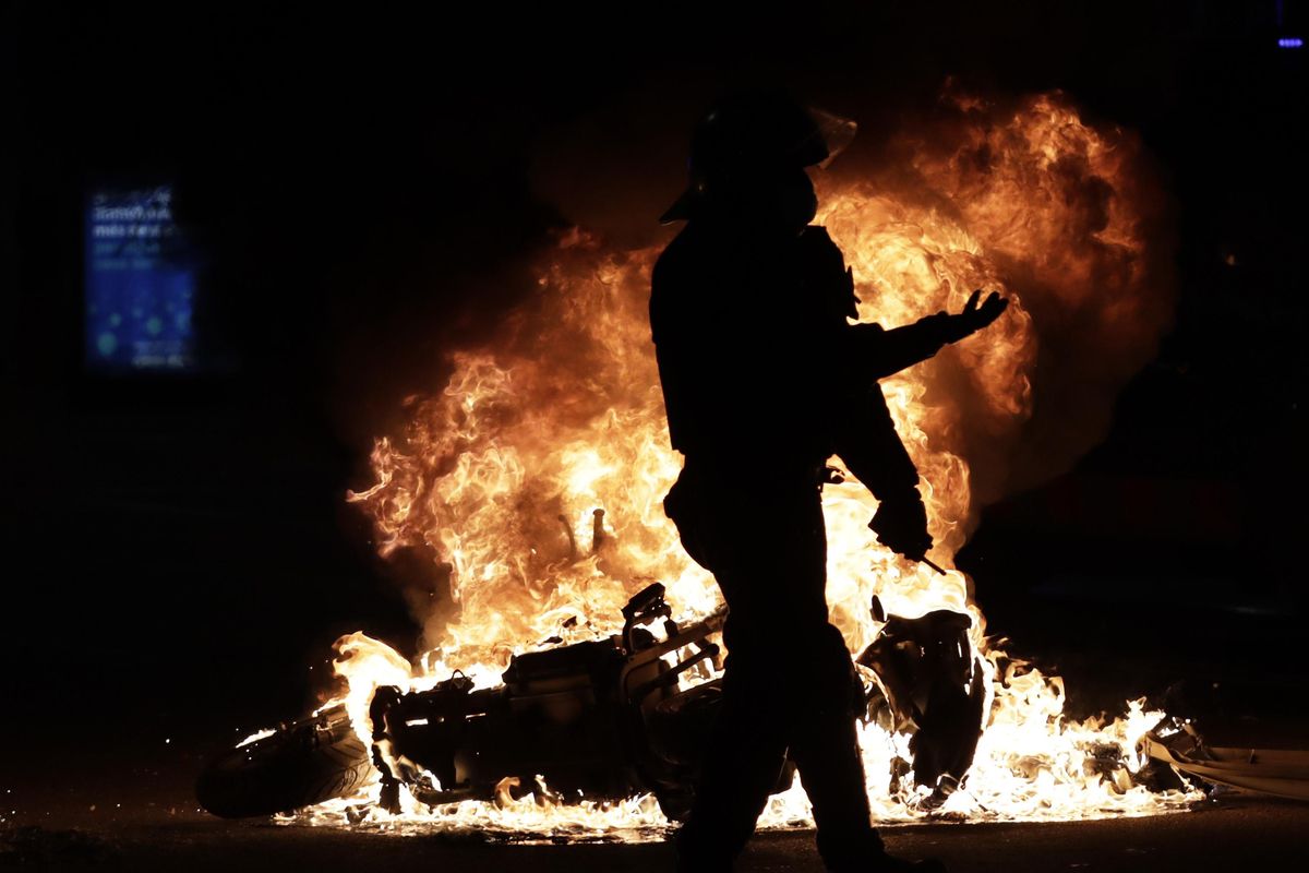 Un mosso d’Esquadra, ante una moto en llamas durante las protestas por la prisión de Pablo Hasél. Un mosso d’Esquadra, ante una moto en llamas durante las protestas por la prisión de Pablo Hasél.
