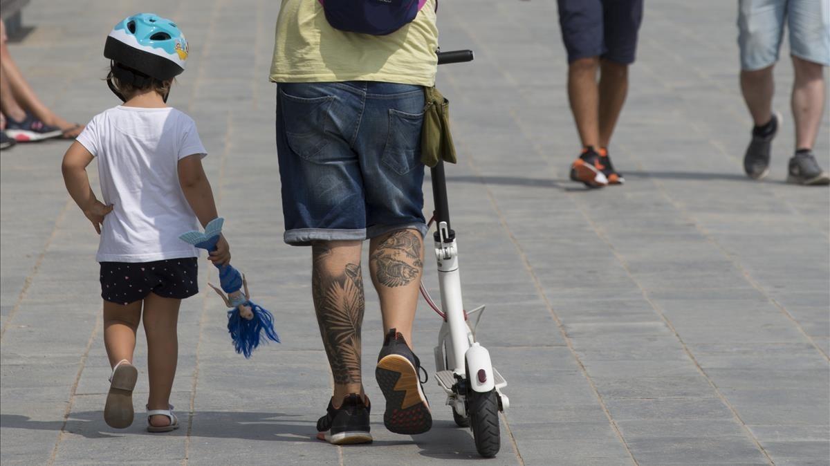 Un padre y su hijo pasean con un patinete eléctrico.