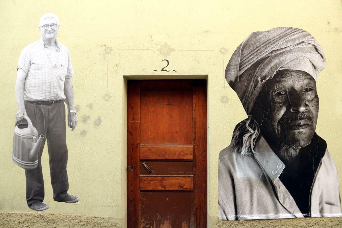 En una fachada de Avià, a un lado, un vecino, y en el otro, un hombre de origen africano. En una fachada de Avià, a un lado, un vecino, y en el otro, un hombre de origen africano.