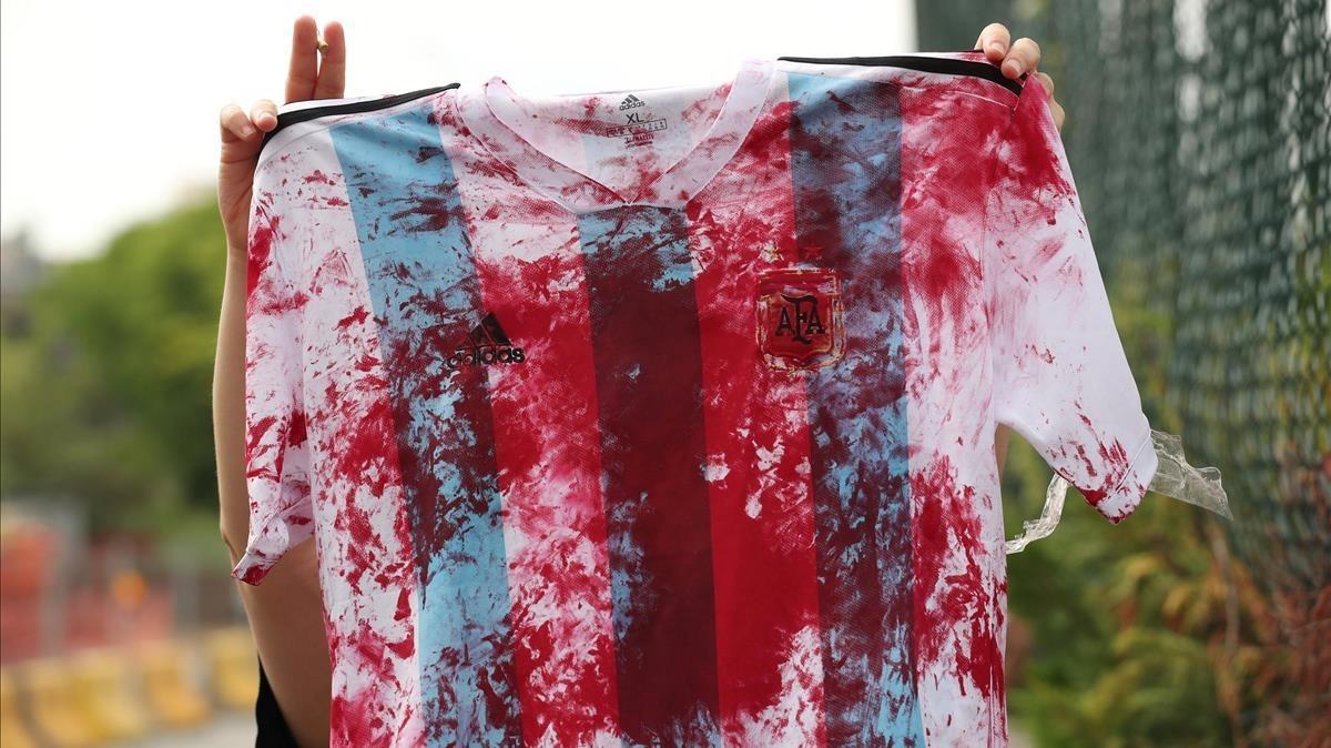 Una mujer Palestina muestra la camiseta de la selección Argentina manchada de sangre en la Ciutat Esportiva Joan Gamper.