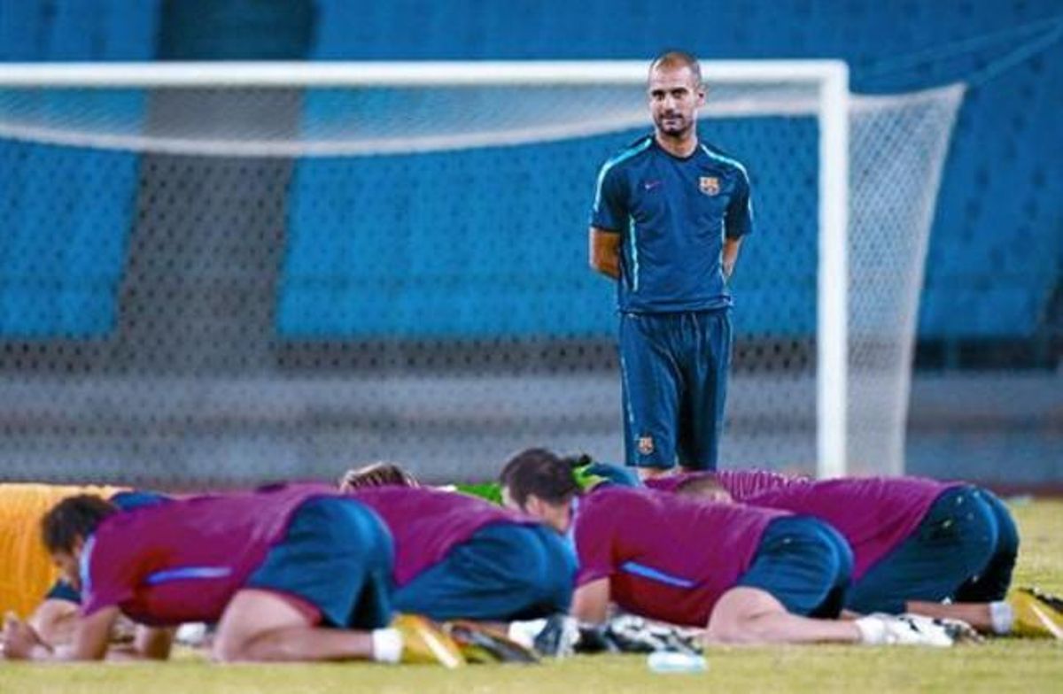 Los jugadores del Barça, arrodillados, realizan ejercicios físicos ante Guardiola, ayer en Pekín. Los jugadores del Barça, arrodillados, realizan ejercicios físicos ante Guardiola, ayer en Pekín.
