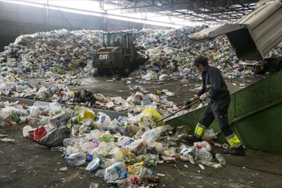 Un empleado trabaja con residuos en las instalaciones de la planta de tratamiento y selección de envases de Gavà, para su posterior reciclaje.