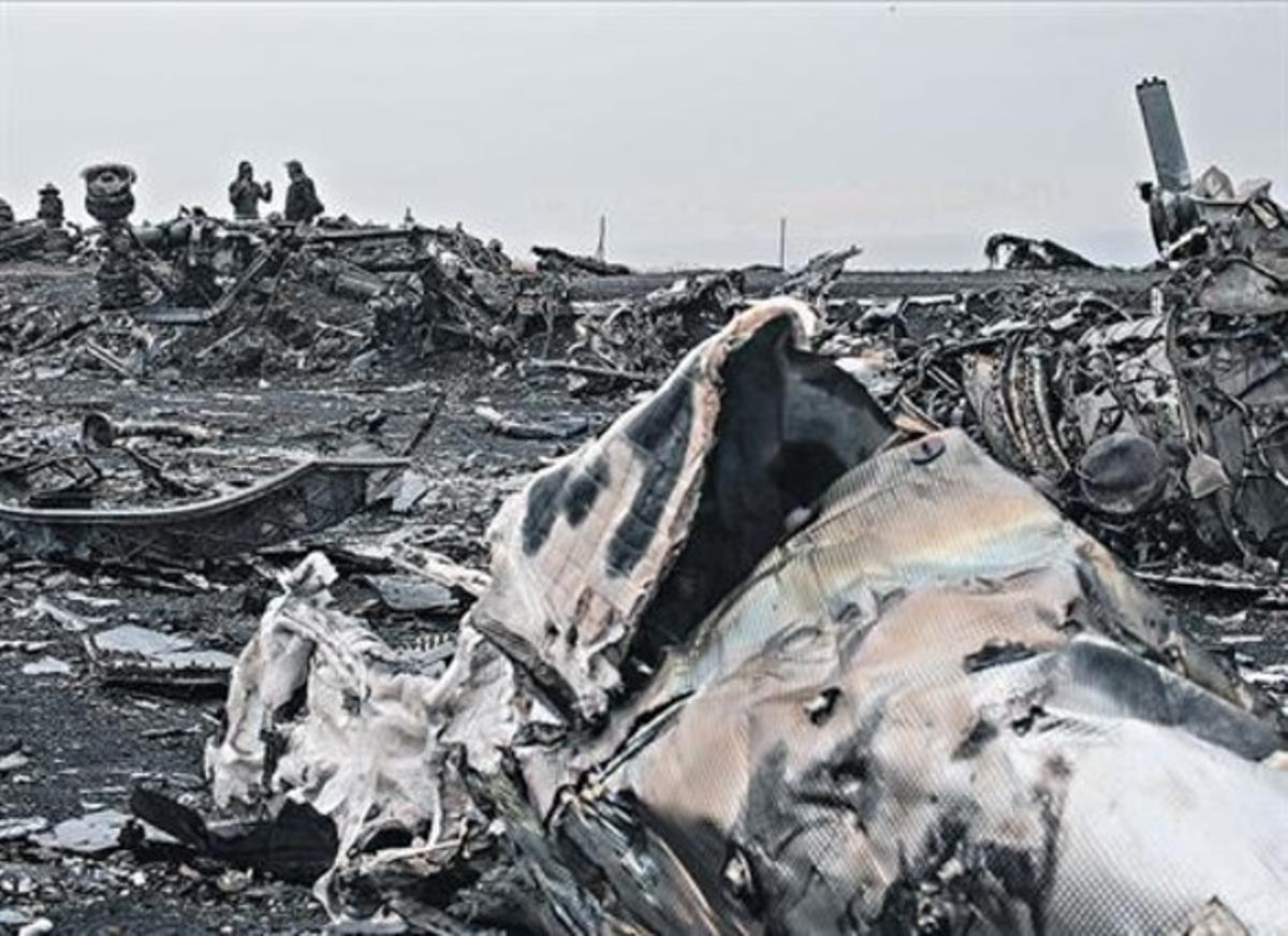 Dos civils observaven les restes de l’avió abatut el 17 de juliol a l’est d’Ucraïna.