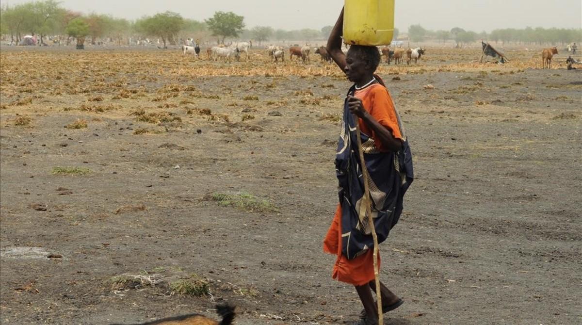 Una mujer desplazada interna en Sudán del Sur lleva agua al campamento en el que se refugia.