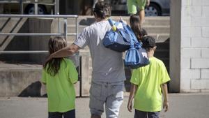 Un padre carga con las bolsas de deporte de sus hijos, en un club deportivo de Barcelona
