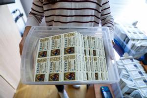 Una trabajadora de una administración de loterías de Barcelona lleva una caja con décimos de la Lotería de Navidad 2022.