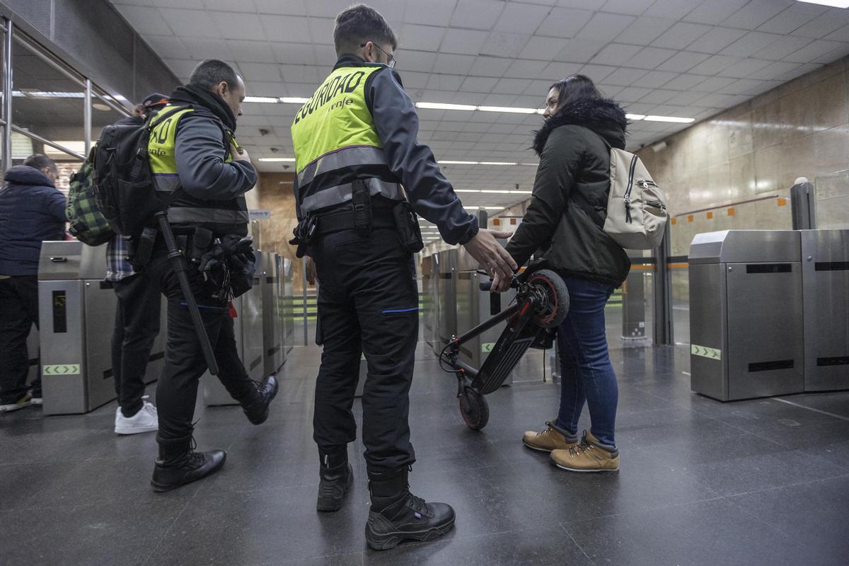 Guardias de seguridad advierten a una usuaria con un patinete eléctrico en la estación de Clot, la primera mañana de prohibición