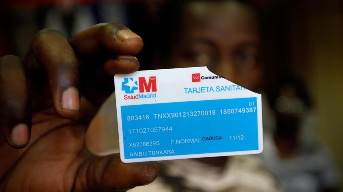 Un inmigrante muestra una tarjeta sanitaria rota. 