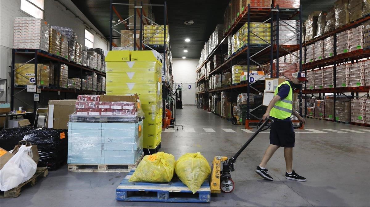 Un operario traslada comida en el almacén del Banco de Alimentos de Barcelona.