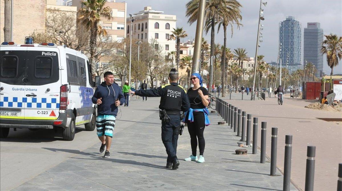 Un agente de la Guardia Urbana da el alto a una pareja de ’runners’ en la Barceloneta.