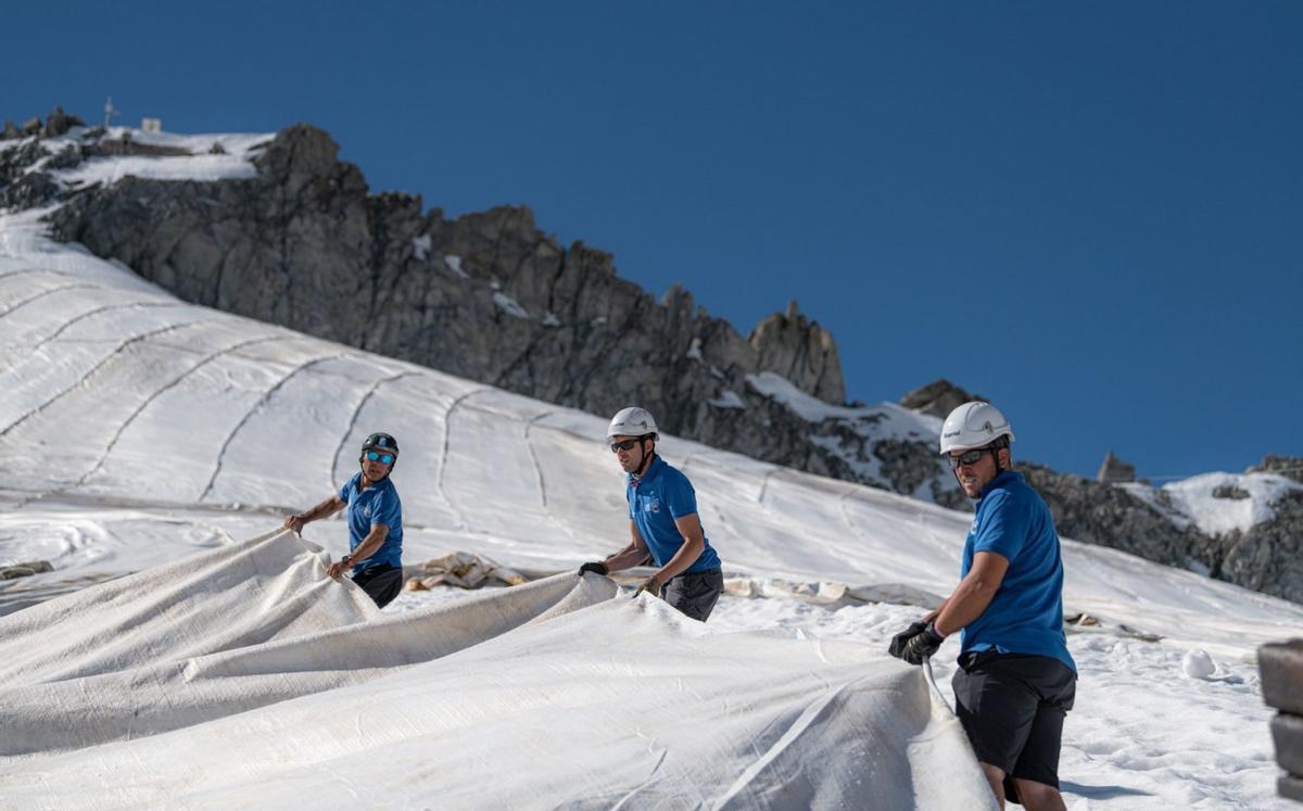 Operarios extendiendo una manta sobre el glaciar italiano