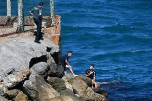Unos guardias civiles atienden a un marroquí que llegó este lunes a nado a Ceuta.