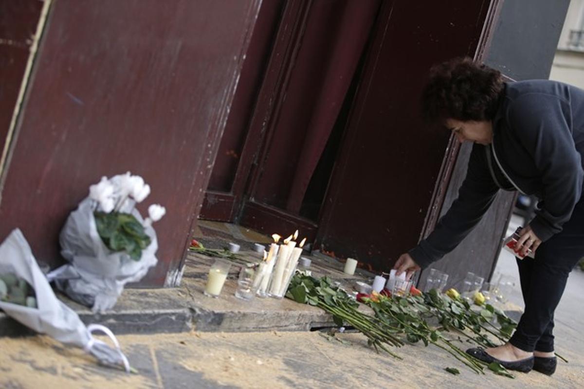 Una mujer deja velas y flores en la puerta del bar Carillon, situado en el décimo distrito de París. Una mujer deja velas y flores en la puerta del bar Carillon, situado en el décimo distrito de París.