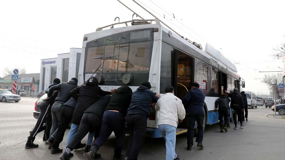 Varias personas intentan mover un autobús eléctrico para por el apagón en Bishkek, Kirguistán. Varias personas intentan mover un autobús eléctrico para por el apagón en Bishkek, Kirguistán.
