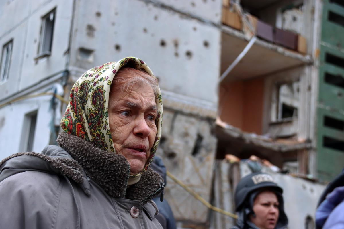 Una mujer se encuentra frente a un edificio residencial muy dañado, después de la retirada de las tropas rusas de la ciudad de Chernihiv.