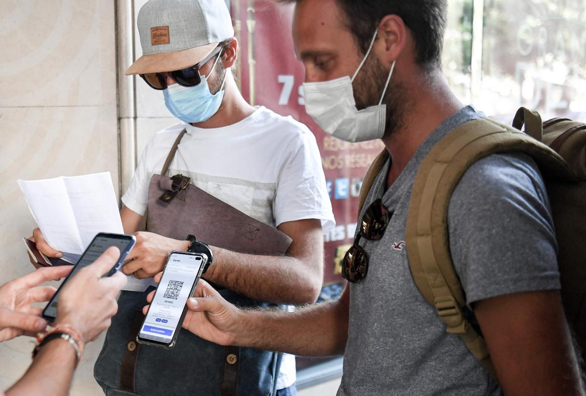 Unos espectadores enseñan su pasaporte sanitario antes de entrar al cine en París.