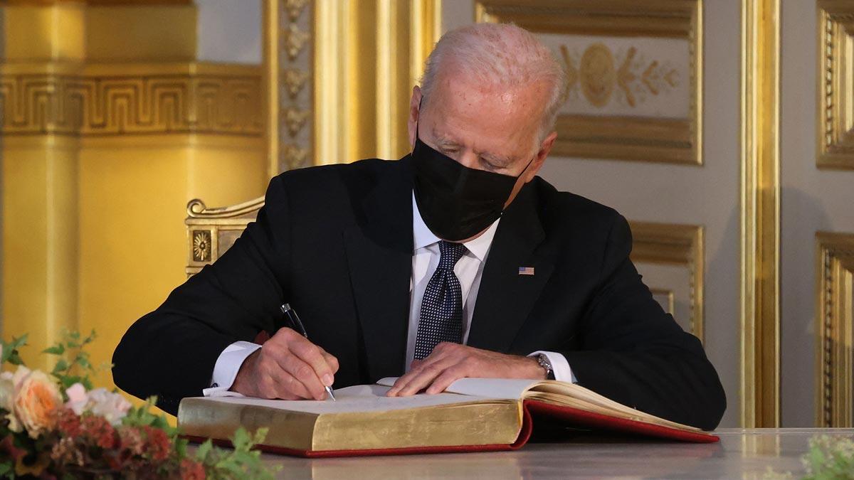 Biden firma en el libro de visitas durante su encuentro con el rey Felipe de Bélgica.