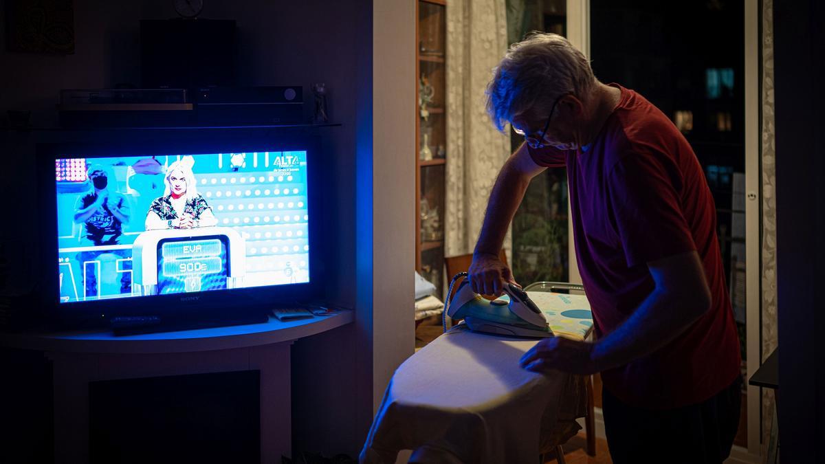 Subida histórica del precio de la luz. Un hombre realiza algunas tareras domésticas frente al televisor