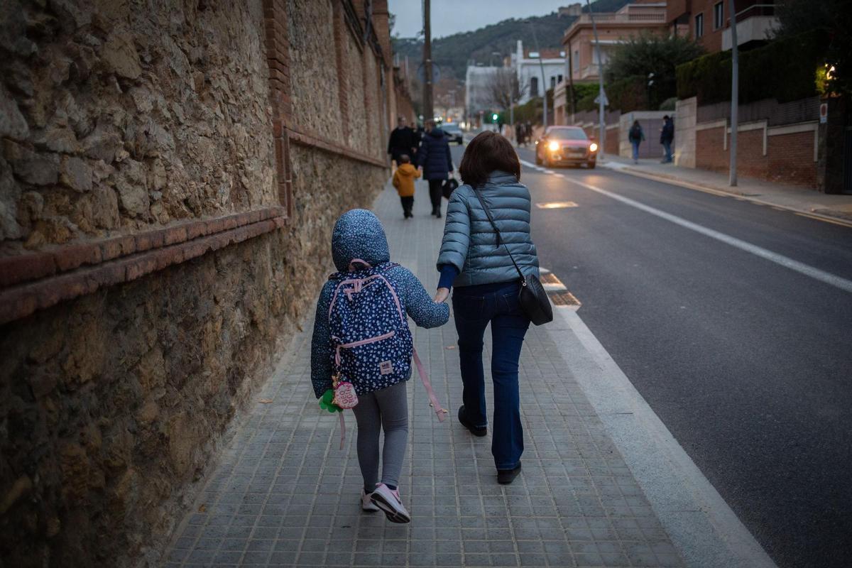 Una mujer lleva de la mano a un niño a clase Una mujer lleva de la mano a un niño a clase