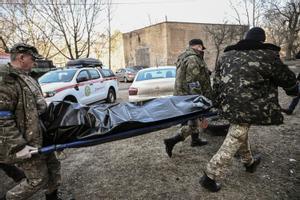 Varios muertos en un ataque contra un barrio residencial en Kiev. En la foto, militares ucranianos llevan un cadáver en una bolsa tras el bombardeo.