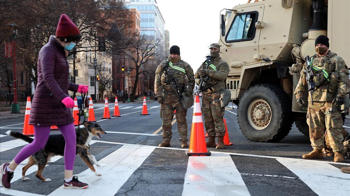 Una persona cruza la calle en un bloqueo de carretera custodiado por miembros de la Guardia Nacional, en Washington. 