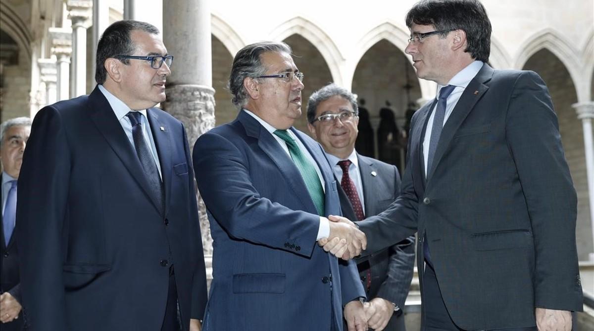 El presidente de la Generalitat, Carles Puigdemont, saluda al ministro del Interior, Juan Ignacio Zoido, ante el ’conseller’ de Interior, Jordi Jané, el 10 de julio, antes del comienzo de la reunión de la Junta de Seguridad.