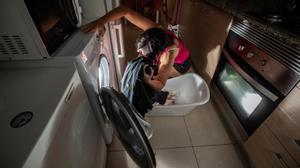 Una mujer pone una lavadora en horario de tarifa más baja de electricidad