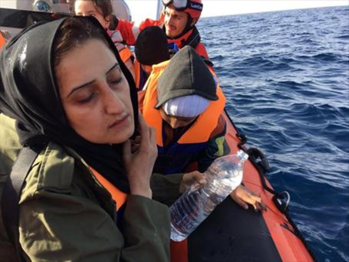 Una madre llora rodeada de sus hijos en una barca de rescate de Open Arms.