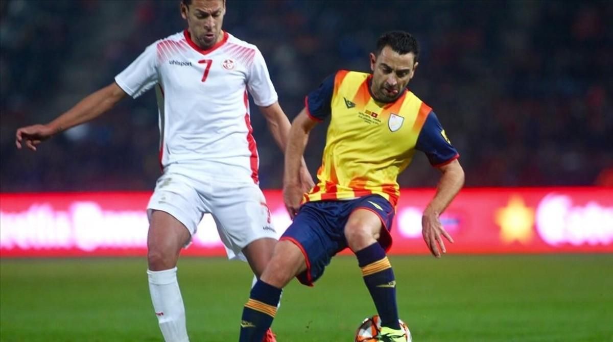 Xavi controla el balón en Montilivi ante Msakni, que marcó los tres goles de Túnez. Xavi controla el balón en Montilivi ante Msakni, que marcó los tres goles de Túnez.