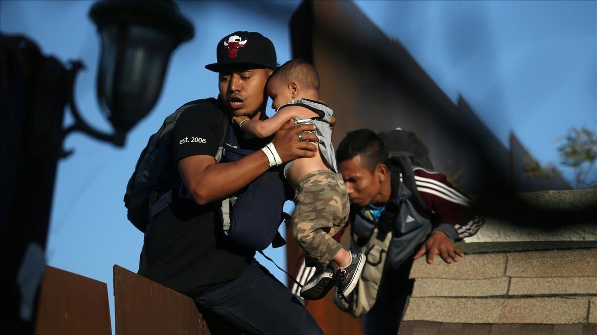 Los migrantes de la caravana intentan saltar el muro desde Tijuana a EEUU.