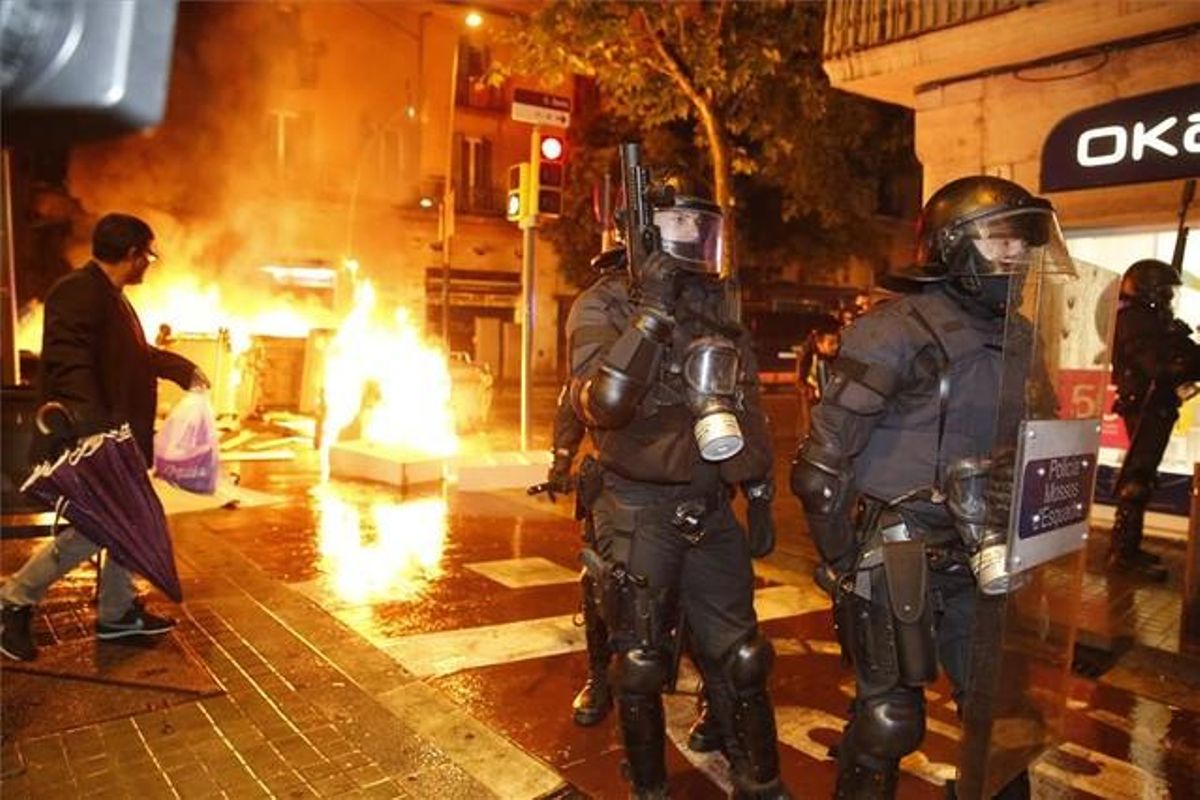 Un grupo de mossos, delante de varios contenedores en llamas en Sants. Un grupo de mossos, delante de varios contenedores en llamas en Sants.
