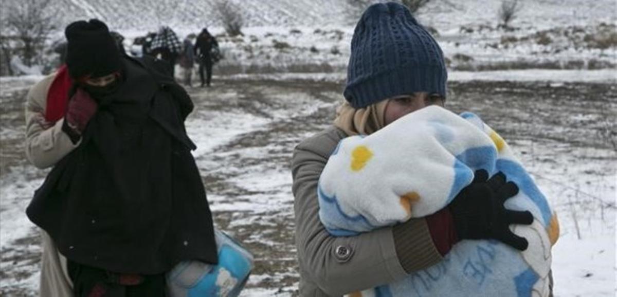 Una mujer migrante protege a su hijo con una manta mientras camina cerca de Miratovac (Serbia), este lunes.
