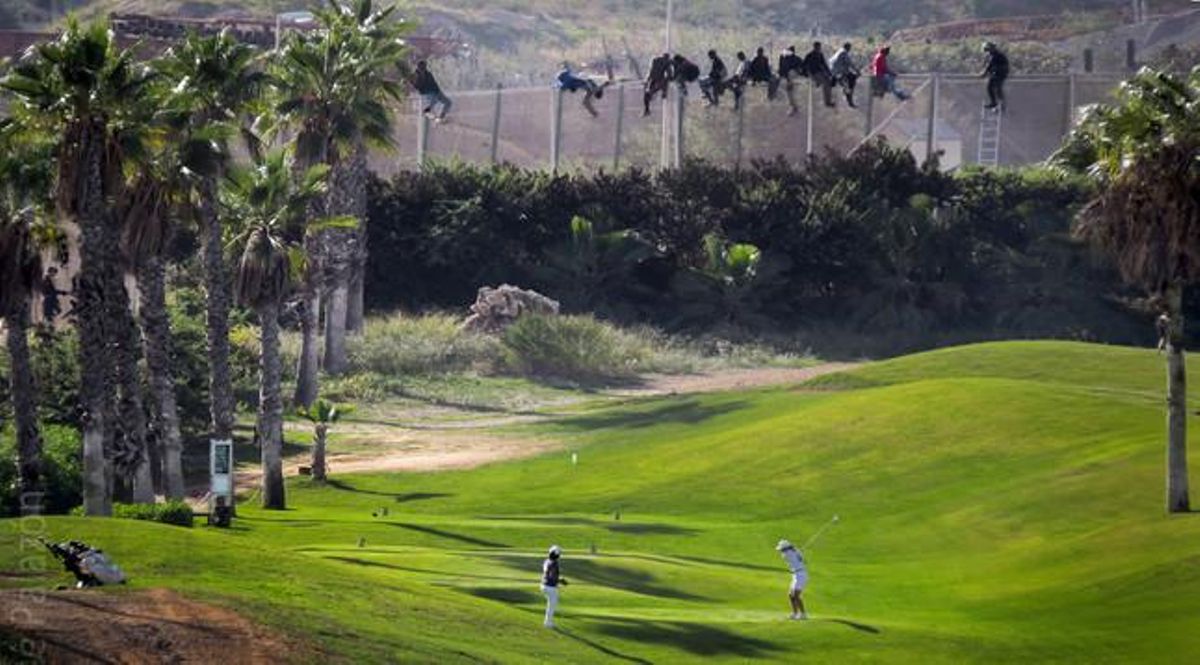 Un grupo de inmigrantes tratan de saltar la valla de Melilla junto a un campo donde juegan dos golfistas. Un grupo de inmigrantes tratan de saltar la valla de Melilla junto a un campo donde juegan dos golfistas.
