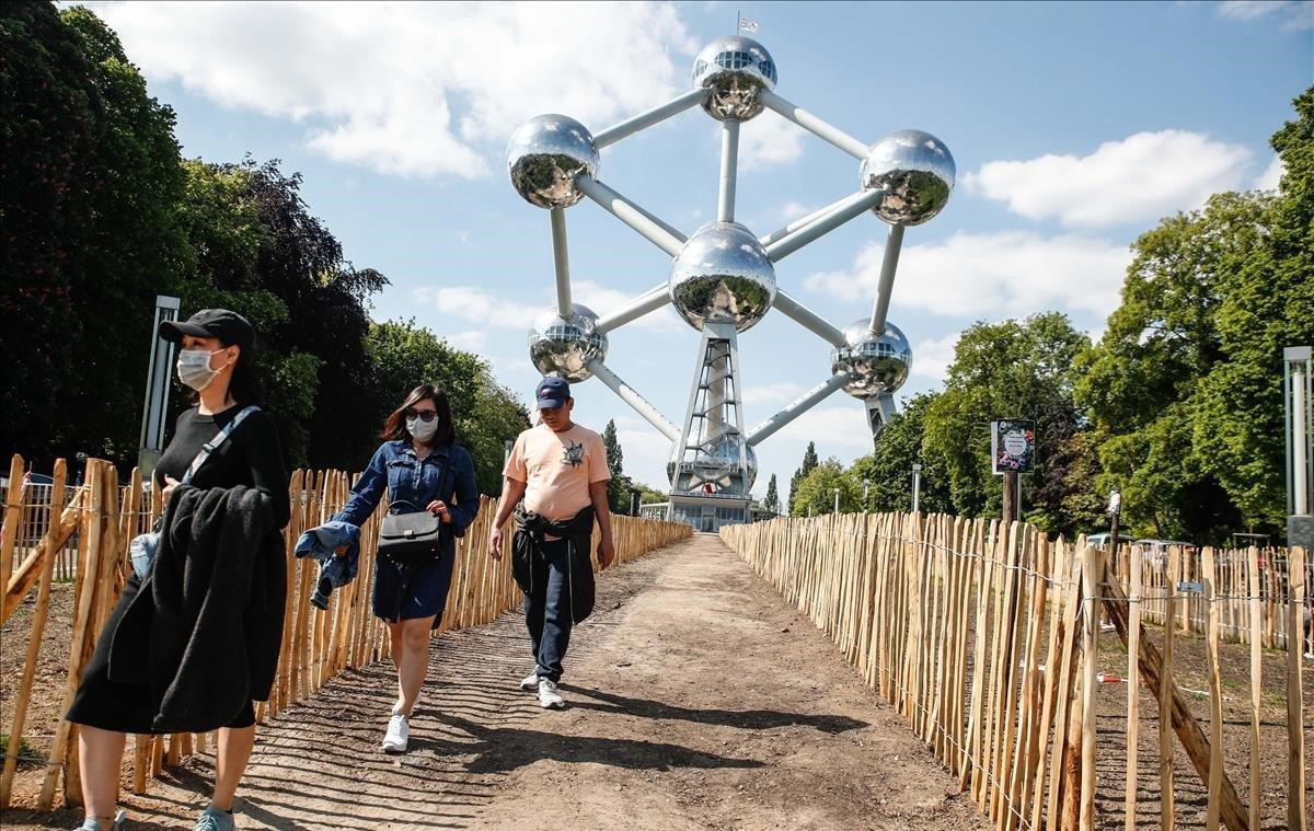 Unas personas con mascarillas pasean alrededor del Atomium de Bruselas, este lunes, coincidiendo con la reunión de la OMS que se coordina desde la capital europea.