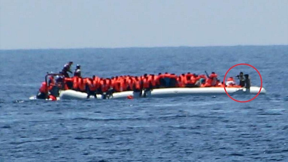 Unos guardacostas libios apuntan con sus armas a un grupo de inmigrantes y refugiados que navegan en una barca por el Mediterráneo, el 24 de mayo. Unos guardacostas libios apuntan con sus armas a un grupo de inmigrantes y refugiados que navegan en una barca por el Mediterráneo, el 24 de mayo.