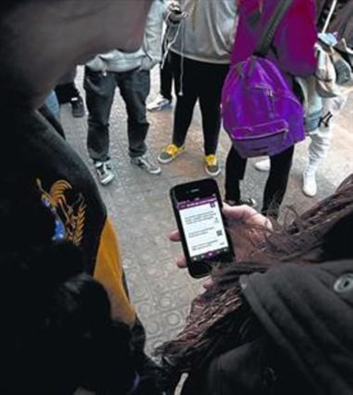 Unos usuarios consultan una aplicación en un teléfono móvil. Unos usuarios consultan una aplicación en un teléfono móvil.