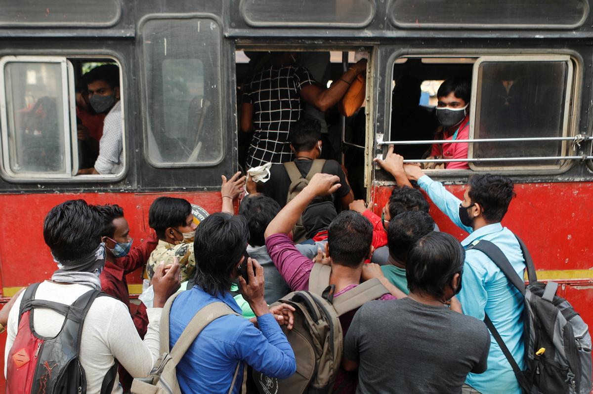 Un grupo de gente se apresura a subir a una autobús en Mumbai (India).